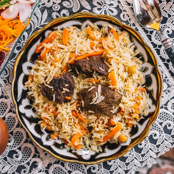 A close-up of Indian pilaf with rice, meat, carrots, and chickpeas in a decorative bowl.